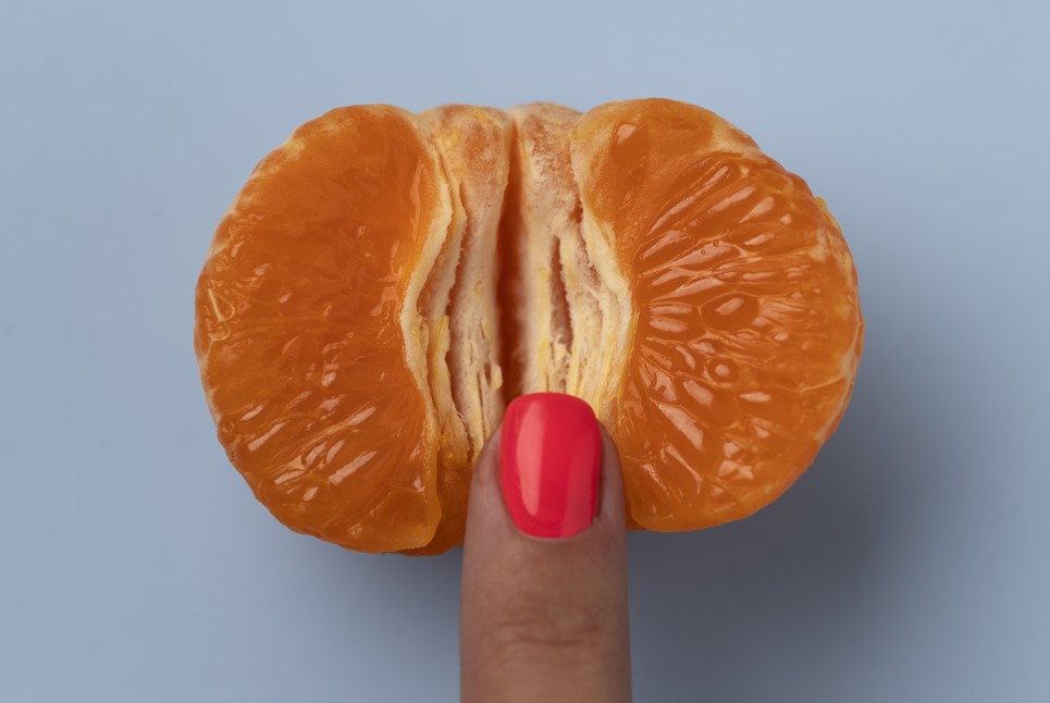 An orange being touched by a finger.